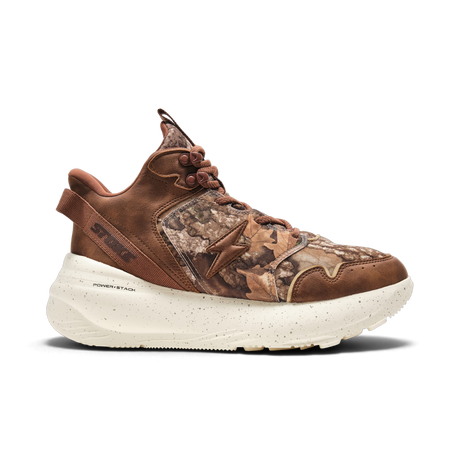 A single mid-top athletic sneaker shown in profile against a solid white background. The shoe features brown leather panels, a brown and beige leaf camouflage pattern on the side, and a thick, speckled off-white midsole.