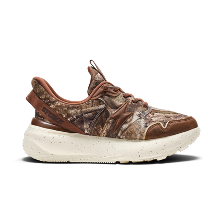 A single sneaker shown in profile against a solid white background. The shoe features a brown and beige woodland camouflage pattern on the upper, with a solid brown leather heel tab displaying the 'STOKE' brand name, a brown star logo on the side, and a thick, speckled off-white midsole.