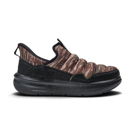 A single slip-on sneaker shown in profile against a white background. The shoe features a brown and beige camouflage pattern on the upper, black mesh side panels, and a thick black speckled sole.